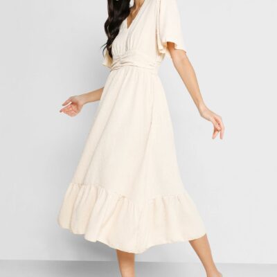 This cream-colored dress features a V-neck, flutter sleeves, and a flattering gathered waist,